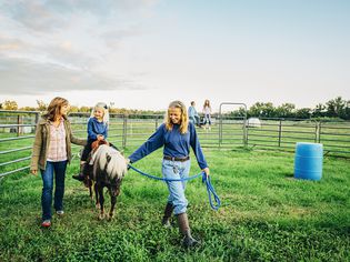 三代白人妇女在农场遛迷你马